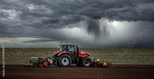 Fotografia, Obraz beautiful landscape with a farmer plowing his fields before the storm