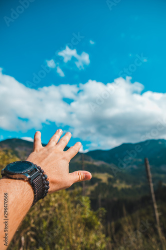 hand with watch and bracelet on the wrist mountains on background