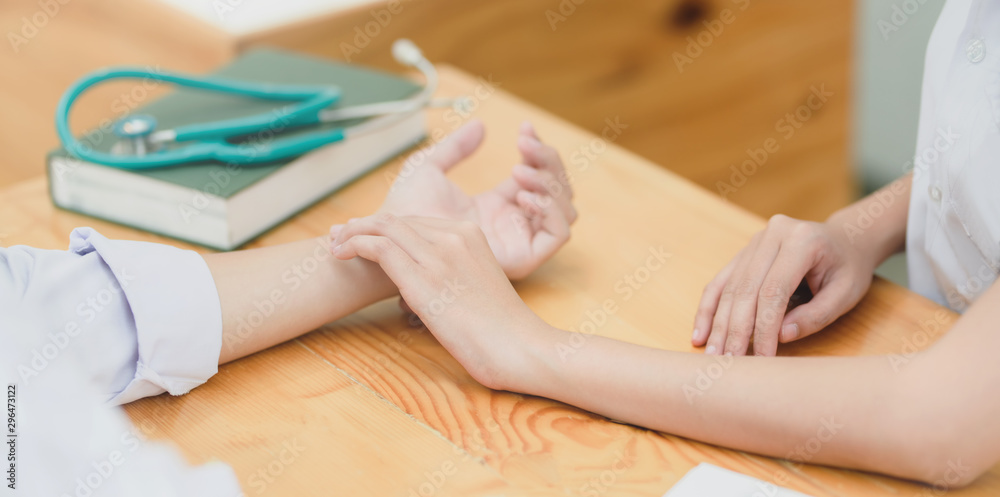 Cropped shot of female doctor checking her patient pulse whit her hand in clinic room