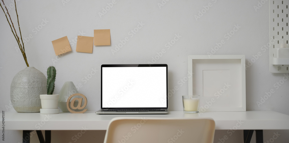 Obraz premium Minimal workspace with blank screen laptop computer with mock up frame and decorations