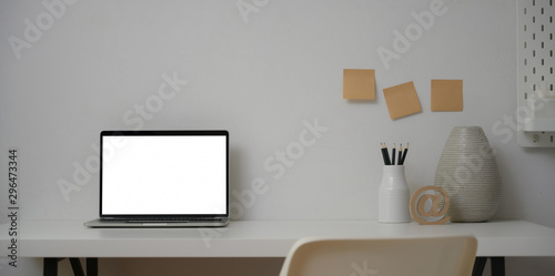 Open laptop computer in minimal workplace with ceramic vase and office supplies © bongkarn