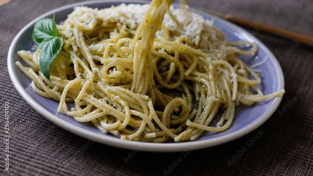 Somebody eating pasta with basil pesto. Typical Italian cheese, pasta on plate just freshly cooked Somebody eating pasta with basil pesto. Typical Italian cheese, pasta on plate just freshly cooked