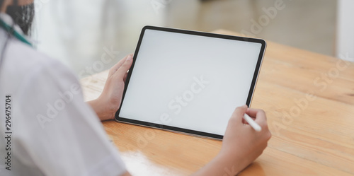 Cropped shot of young female doctor examining the patient chart while using tablet