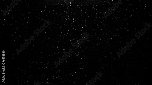 Numerous small air bubbles rise up under crystal clear water, mixing and rise up, swirling softly underwater on the black background with copy space. Underwater bubbles mayhem. Slow motion. Close-up photo