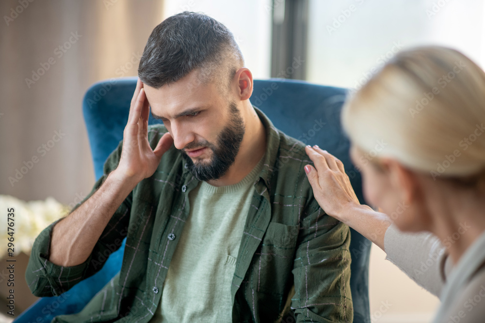 Man having headache while sharing concerns with psychoanalyst Man having headache while sharing concerns with psychoanalyst