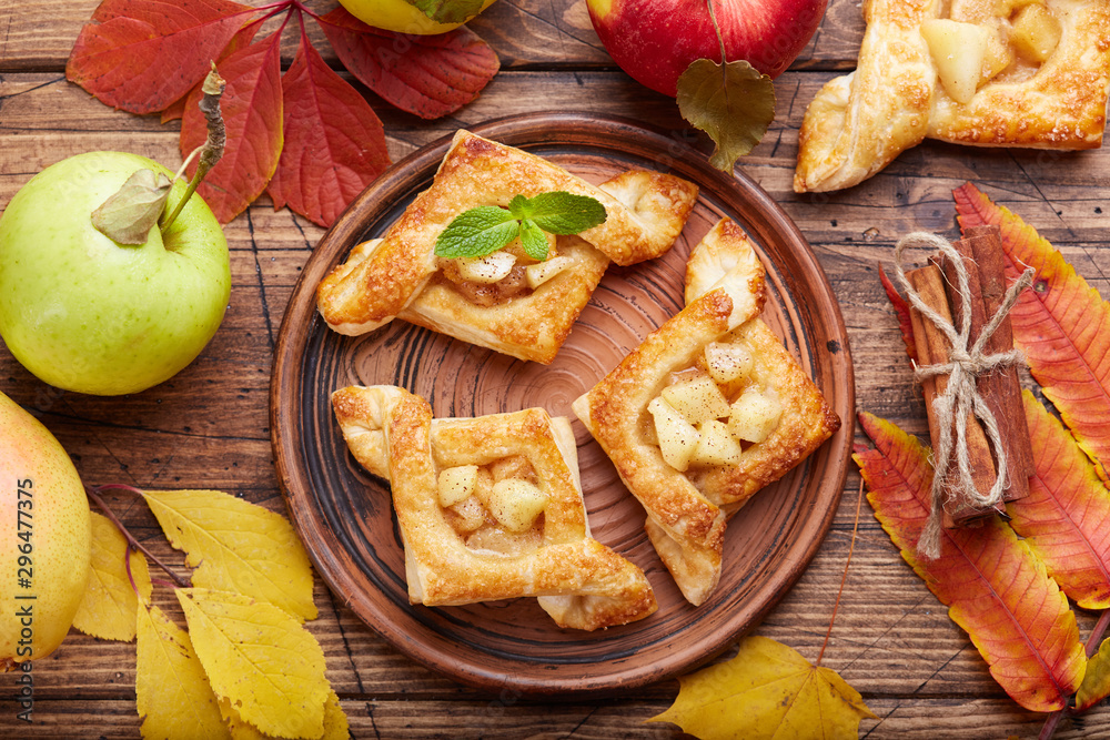 Fototapeta premium Delicious puff pastries with apples, plums and cinnamon. Sweet autumn dessert.