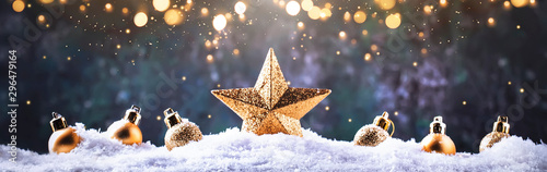 Christmas background with golden star. New Year's decor. Christmas balls in smowdrifts and golden bokeh lights photo