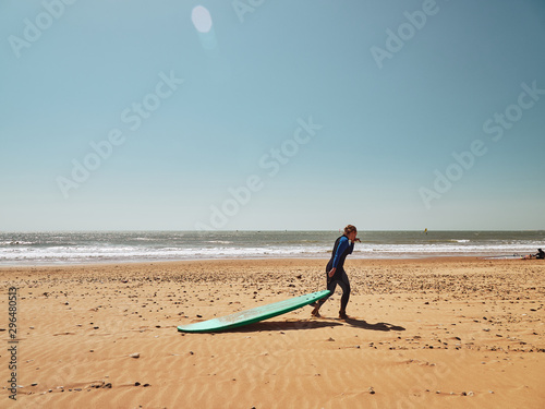 Surfer girl dragging the surf on a sand beach