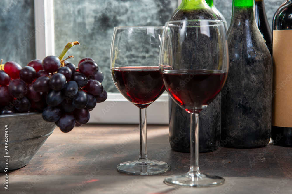 Composition with two wineglasses, grapes and bottles of red wine Composition with two wineglasses, grapes and bottles of red wine