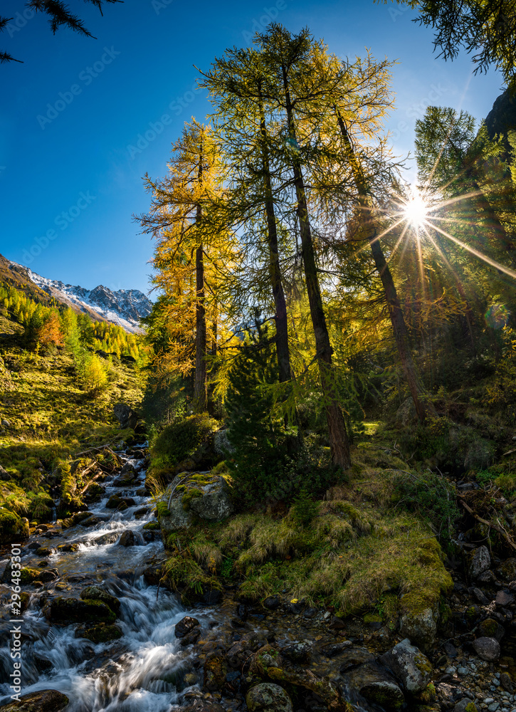 wonderful mountain creek in Val Zeznina with yellow larches and Poz Macun wonderful mountain creek in Val Zeznina with yellow larches and Poz Macun