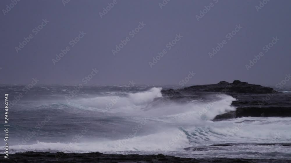 Stormy looking ocean as an extremely strong offshore winds lift the lip of waves breaking on the rocks in slow motion. Stormy looking ocean as an extremely strong offshore winds lift the lip of waves breaking on the rocks in slow motion.