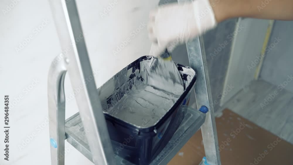 Close up of female hands in gloves mixing grey paint or plaster with a spatula Close up of female hands in gloves mixing grey paint or plaster with a spatula