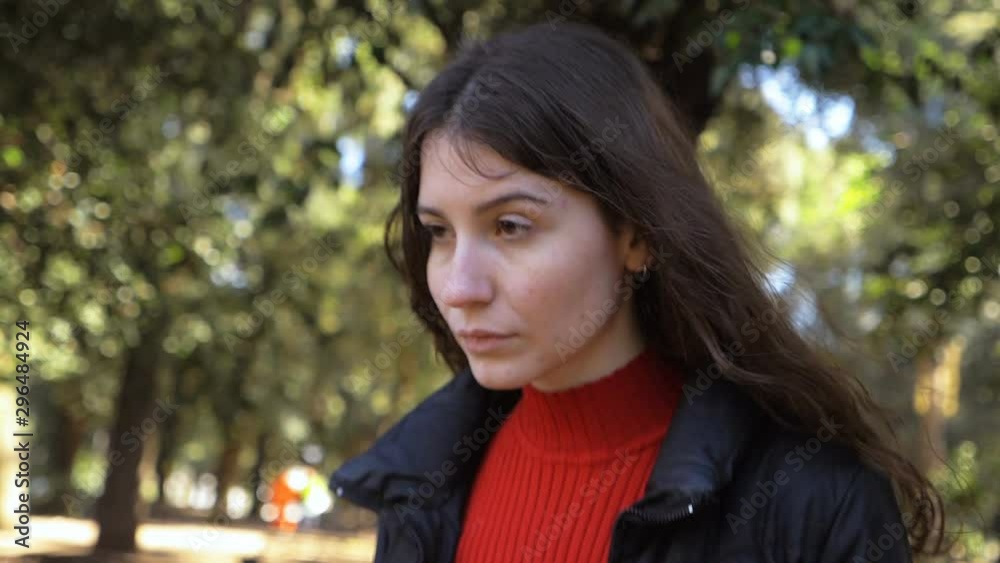 Pensive beautiful young woman walking alone in the park-slow motion Pensive beautiful young woman walking alone in the park-slow motion