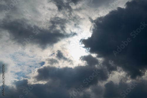 Storm clouds are coming and obscuring the sun. Bad weather. Strong wind and feeling the rain. The clouds are dark blue. The clouds are lit by sunlight.