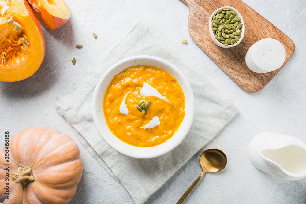 Pumpkin soup with cream on grey stone background. Copy space. Top view. Pumpkin soup with cream on grey stone background. Copy space. Top view.