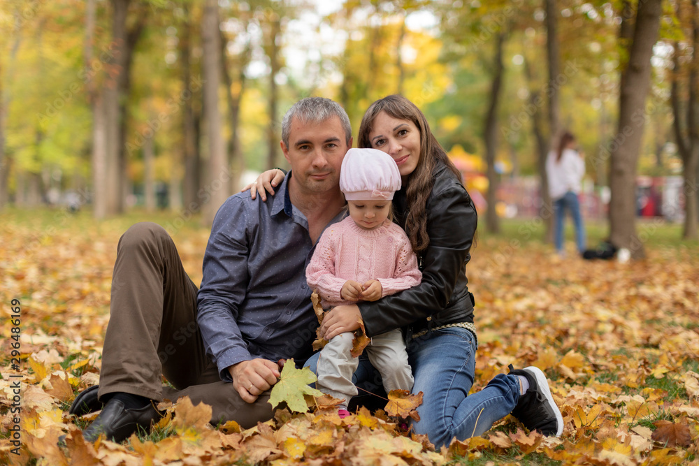 Happy family together in autumn garden/park. Parents with their children are sitting on coverlet in park. Outdoor in full height photo. Family concept Happy family together in autumn garden/park. Parents with their children are sitting on coverlet in park. Outdoor in full height photo. Family concept