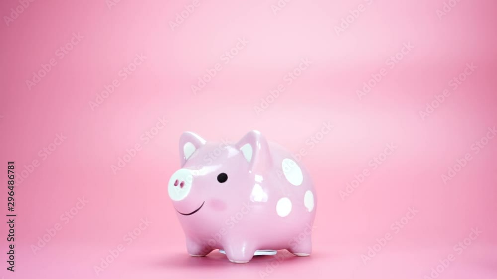 Man putting coin in piggy bank on a pink background. Saving money concept. Man putting coin in piggy bank on a pink background. Saving money concept.