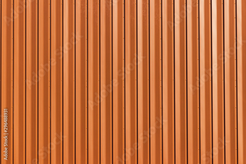 Building with wall of orange metal. Corrugated texture, galvanized steel surface. Abstract architectural pattern for background with copy space