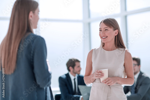 businesswoman with a glass of coffee discussing something with her colleague