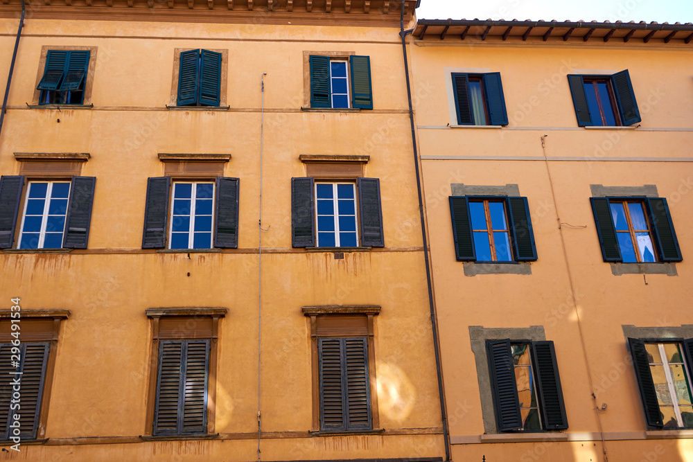 Bright colorful facade of old Italian building with windows, balconies and shutters. Pisa, Italy.