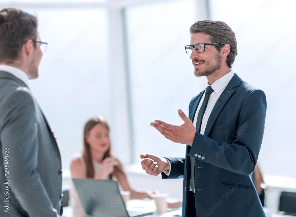 businessman explaining something to his colleague standing in the office. businessman explaining something to his colleague standing in the office.