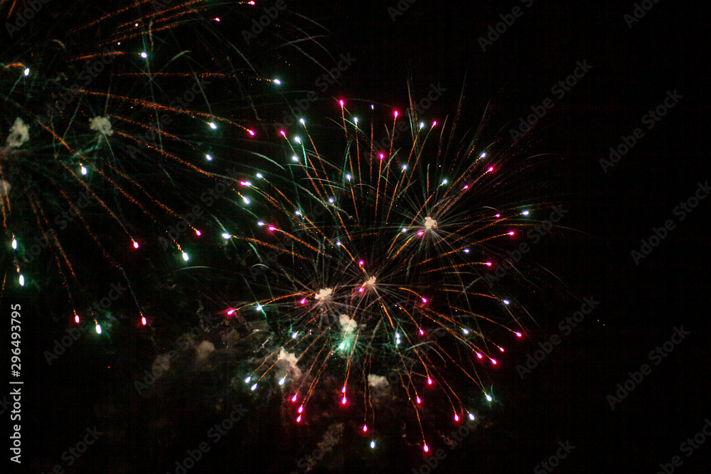 Fireworks in the sky. Salute exploded in a colorful ball in the night sky. Sparks and lights on a black background. Fireworks in the sky. Salute exploded in a colorful ball in the night sky. Sparks and lights on a black background.