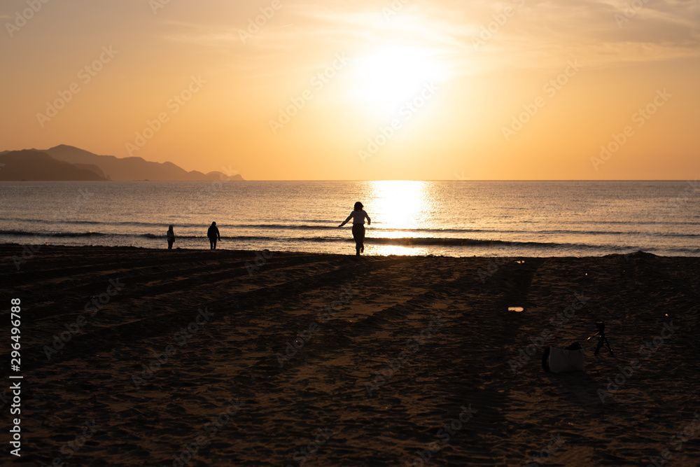 夕日に向かって砂浜を走る女性 夕日に向かって砂浜を走る女性