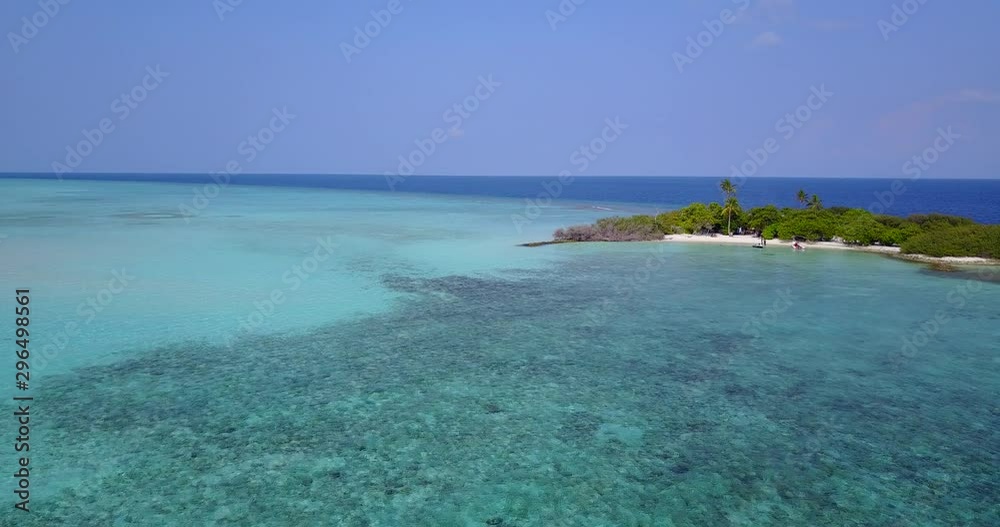 Flying over a shallow sandbar towards a tiny island with a number of tourists on the shore in Indonesia Flying over a shallow sandbar towards a tiny island with a number of tourists on the shore in Indonesia