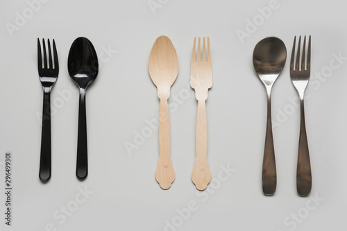 Comparison of reusable metal cutlery, harmful disposable plastic and eco wooden. View from above. Top view. Flat lay.