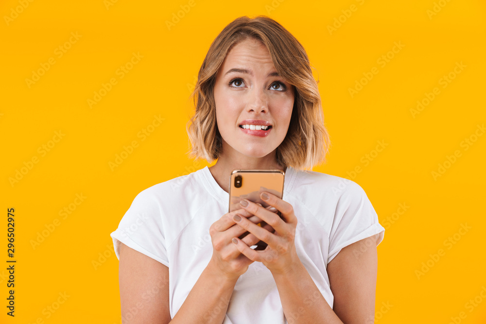 Image of puzzled blond woman looking upward and holding cellphone Image of puzzled blond woman looking upward and holding cellphone