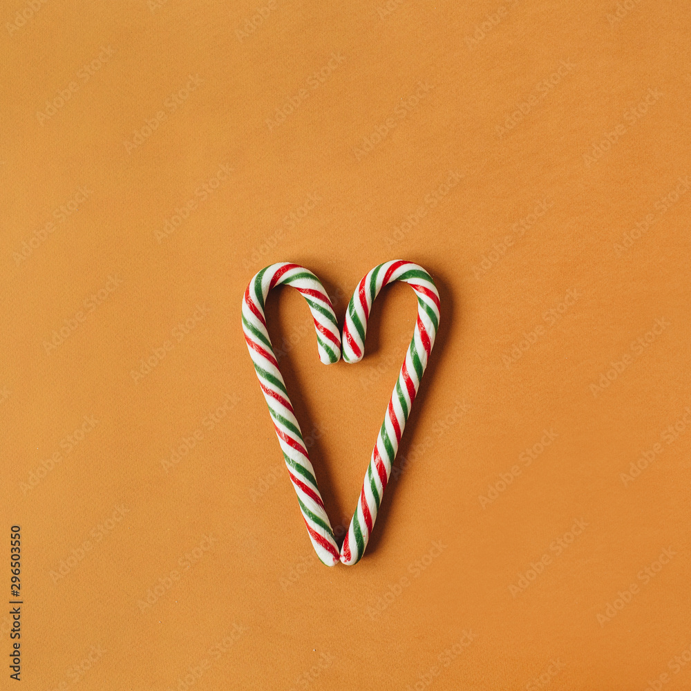 Heart symbol made of traditional stick candies on ginger background. Flat lay, top view Christmas / New Year holiday concept. Heart symbol made of traditional stick candies on ginger background. Flat lay, top view Christmas / New Year holiday concept.
