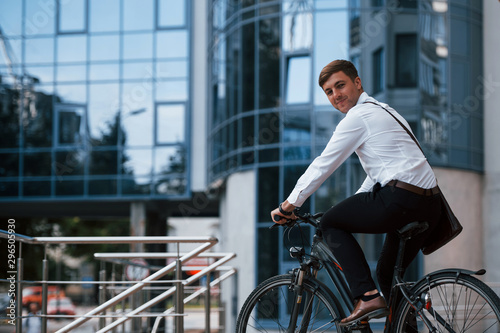 Side view. Businessman in formal clothes with black bicycle is in the city
