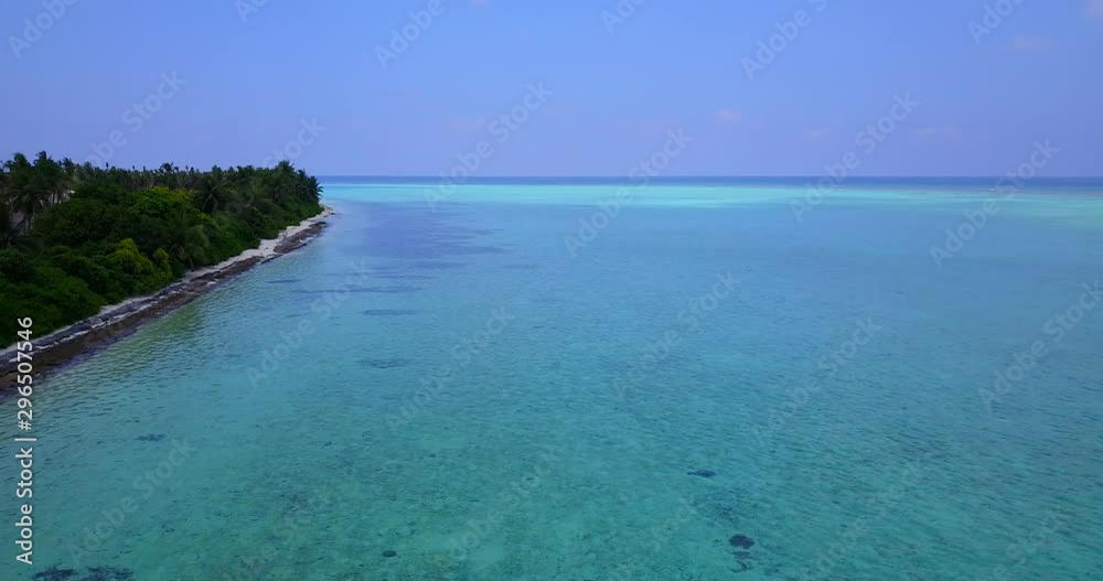 Flying along the coast line of a tropical island with pristine clear water and green trees on the shore with deforestation behind on the island in Indonesia Flying along the coast line of a tropical island with pristine clear water and green trees on the shore with deforestation behind on the island in Indonesia