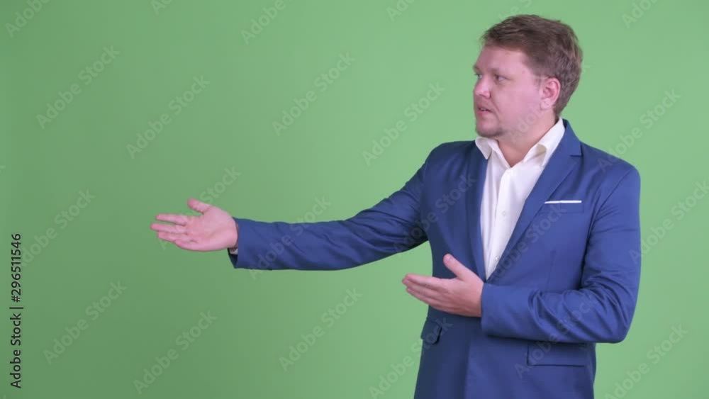 Happy overweight bearded businessman talking while showing something Happy overweight bearded businessman talking while showing something