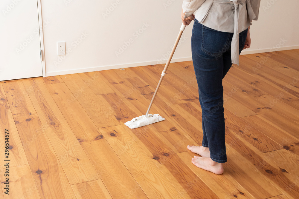 木目の床をモップがけする若い女性の足元