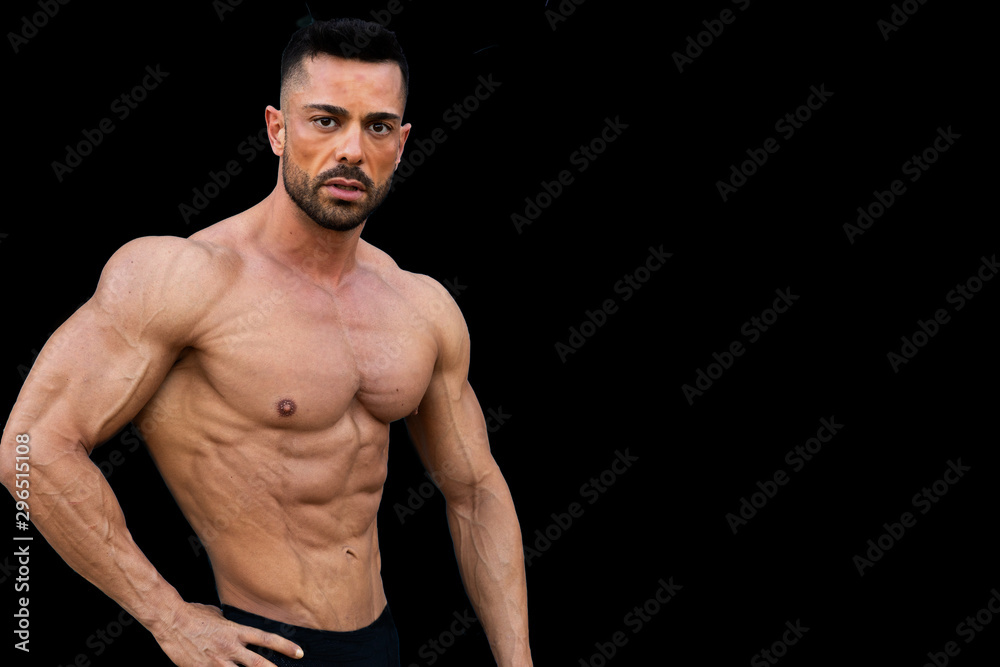 Very muscular fitness model man, posing without shirt. there is a black background