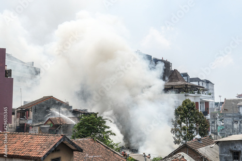 Burning fire flame with smoke on the apartment house roof in the city, view of flames erupting out of the walls and roof of a house