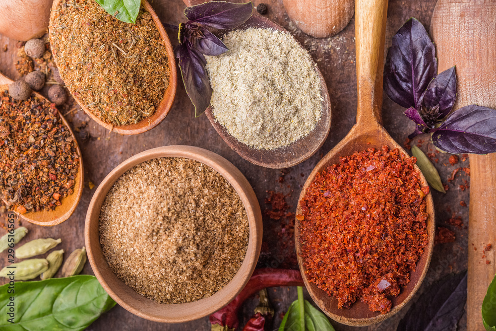 Heaps of various ground spices in wooden spoons on wooden background. Georgian spices, Indian spices, Arabian spices. Spice variety. Herbs and spices Heaps of various ground spices in wooden spoons on wooden background. Georgian spices, Indian spices, Arabian spices. Spice variety. Herbs and spices
