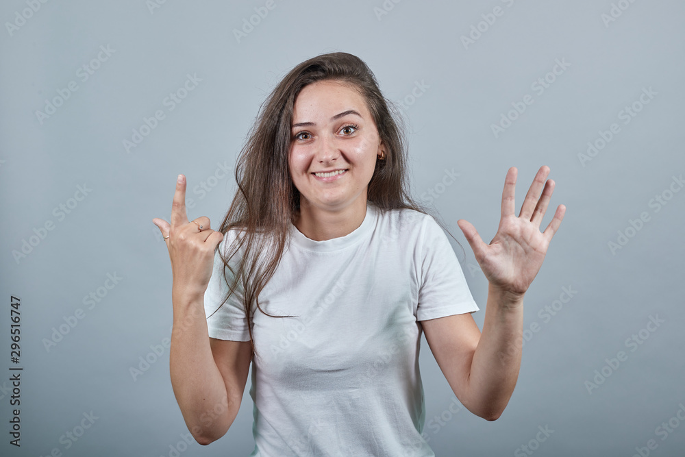 Woman with long hair over colorful wall counting seven with fingers. Person shows two hands with curved fingers, which symbolize number 7 Woman with long hair over colorful wall counting seven with fingers. Person shows two hands with curved fingers, which symbolize number 7
