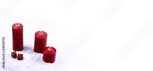 Red Christmas Candle in the Snow stock images. Red Christmas candles on a white background. Three red candles with gift box. Red Christmas candles on a white background with copy space for text