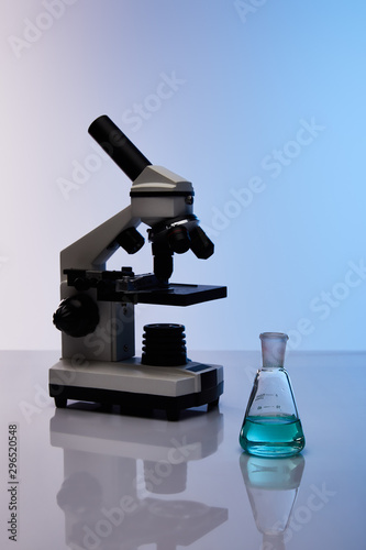 glass flask with colorful blue liquid near microscope