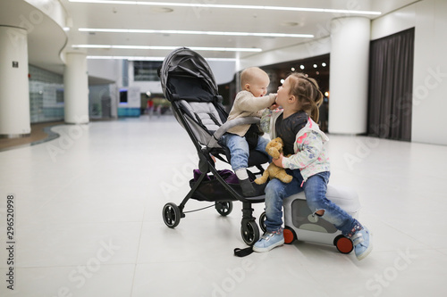 child with suitcases and baby in stroller, airport