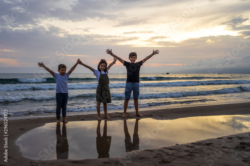 Three kids on a beach at sunset