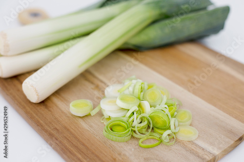 Fresh Leeks and leek round cuttings in a wooden board in a white background