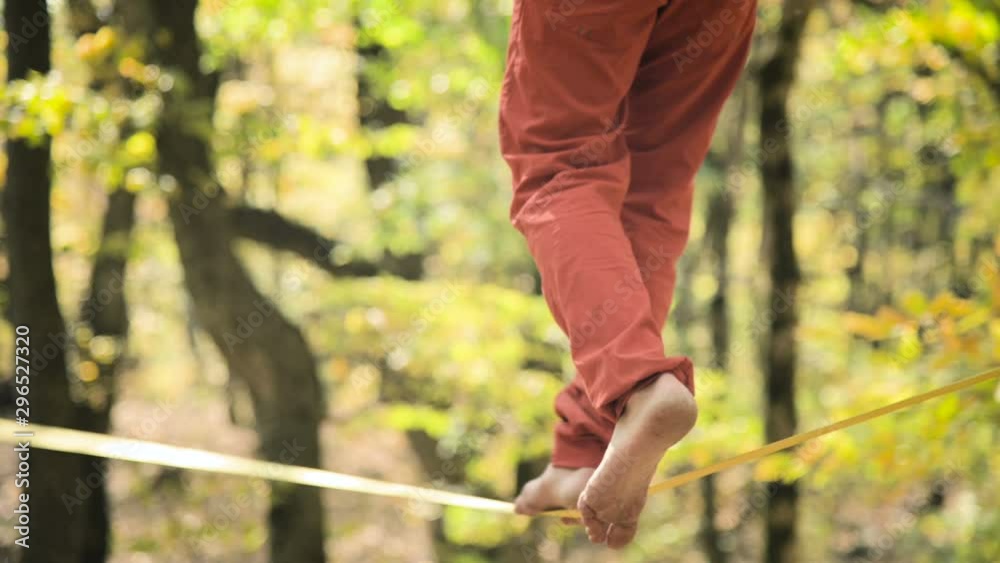 A Slack man aged with a beard in sportswear walks balancing on the slackline. The concept of sports activity at the age of 50. Athlete's foot closeup A Slack man aged with a beard in sportswear walks balancing on the slackline. The concept of sports activity at the age of 50. Athlete's foot closeup