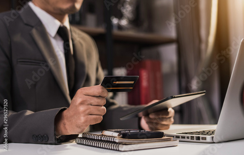 Businessman use credit card to shopping online in internet website shop with computer laptop on work table in office.