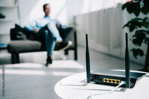 Photography selective focus of black plugged router on white table and businessman sitting o