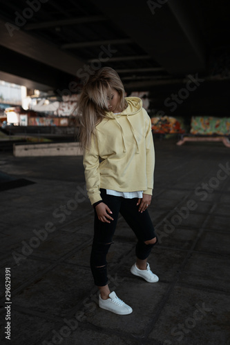 Stylish sexy attractive sport woman walking on urban background in summer day. Sexy pretty beauty young girl portrait wearing in sneakers, jacket, trousers. Seductive trendy model