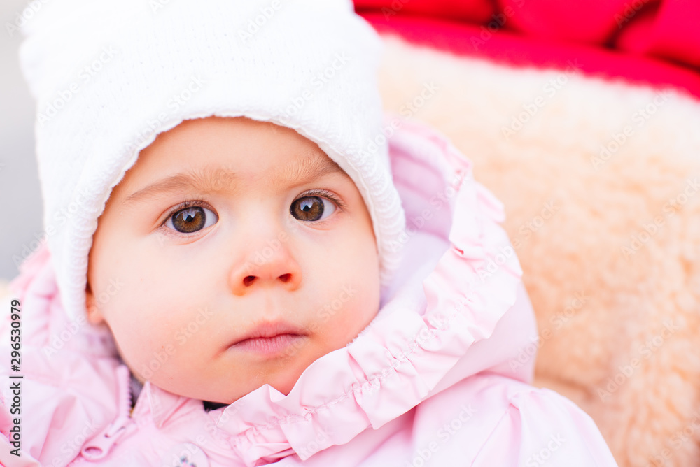 Adorable baby girl with big beautiful eyes and a beanie in stoller Adorable baby girl with big beautiful eyes and a beanie in stoller