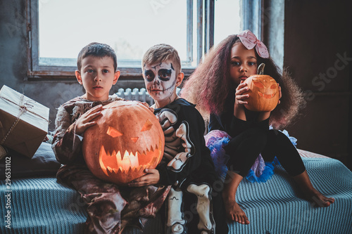 Little pretty kids are ready for Halloween, they are holding carved pumpkins.